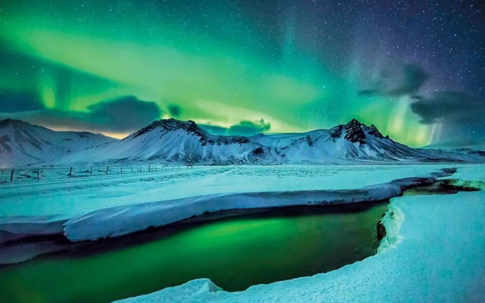 Northern lights over snowy mountains and a lake