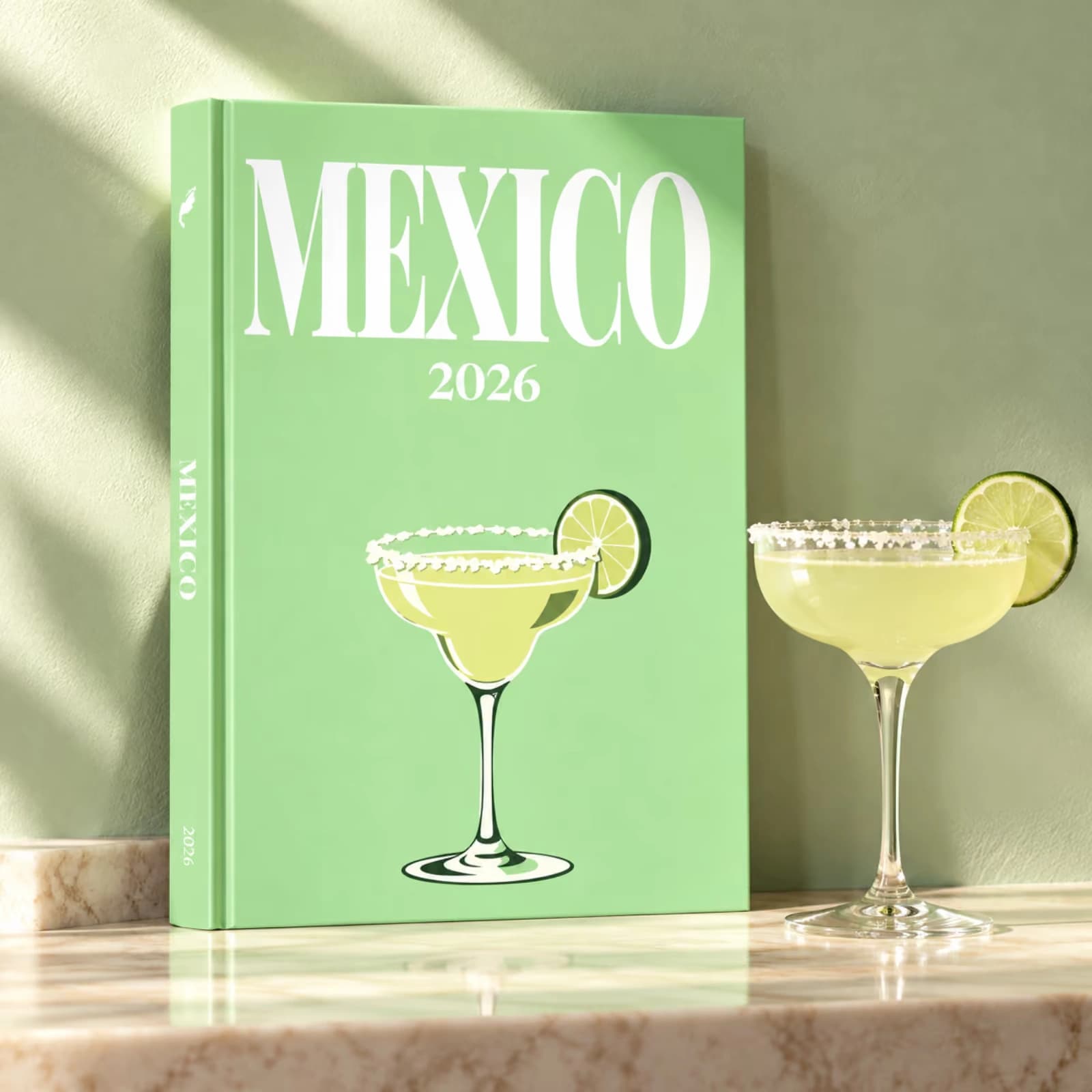 A green Mexico travel photo book with an illustrated margarita, standing beside a real margarita