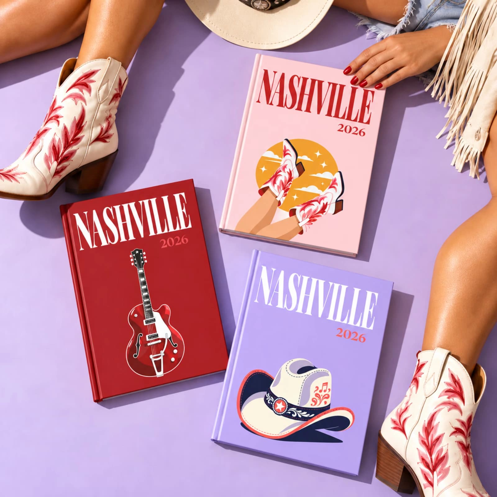 Three Nashville travel photo books with illustrated guitar, boot and cowboy hat covers, beside a pair of cowboy boots