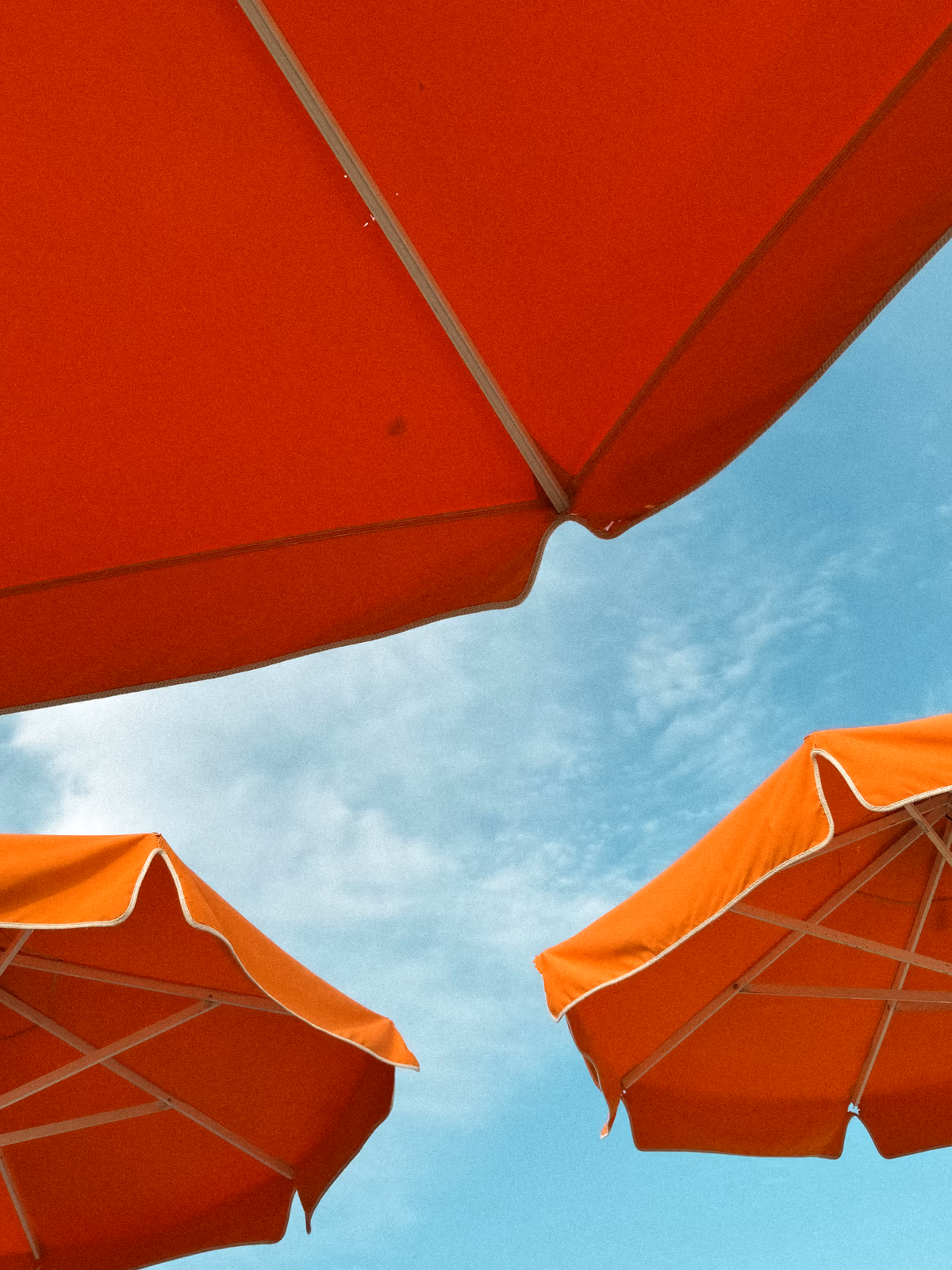 Orange beach umbrellas framing a bright blue sky