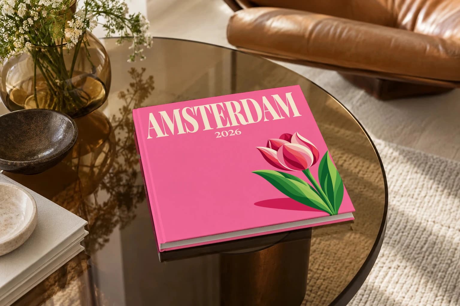 Amsterdam square hardcover photo book with the illustrated cover of the tulip, on a smoked glass coffee table beside a leather armchair in warm afternoon light