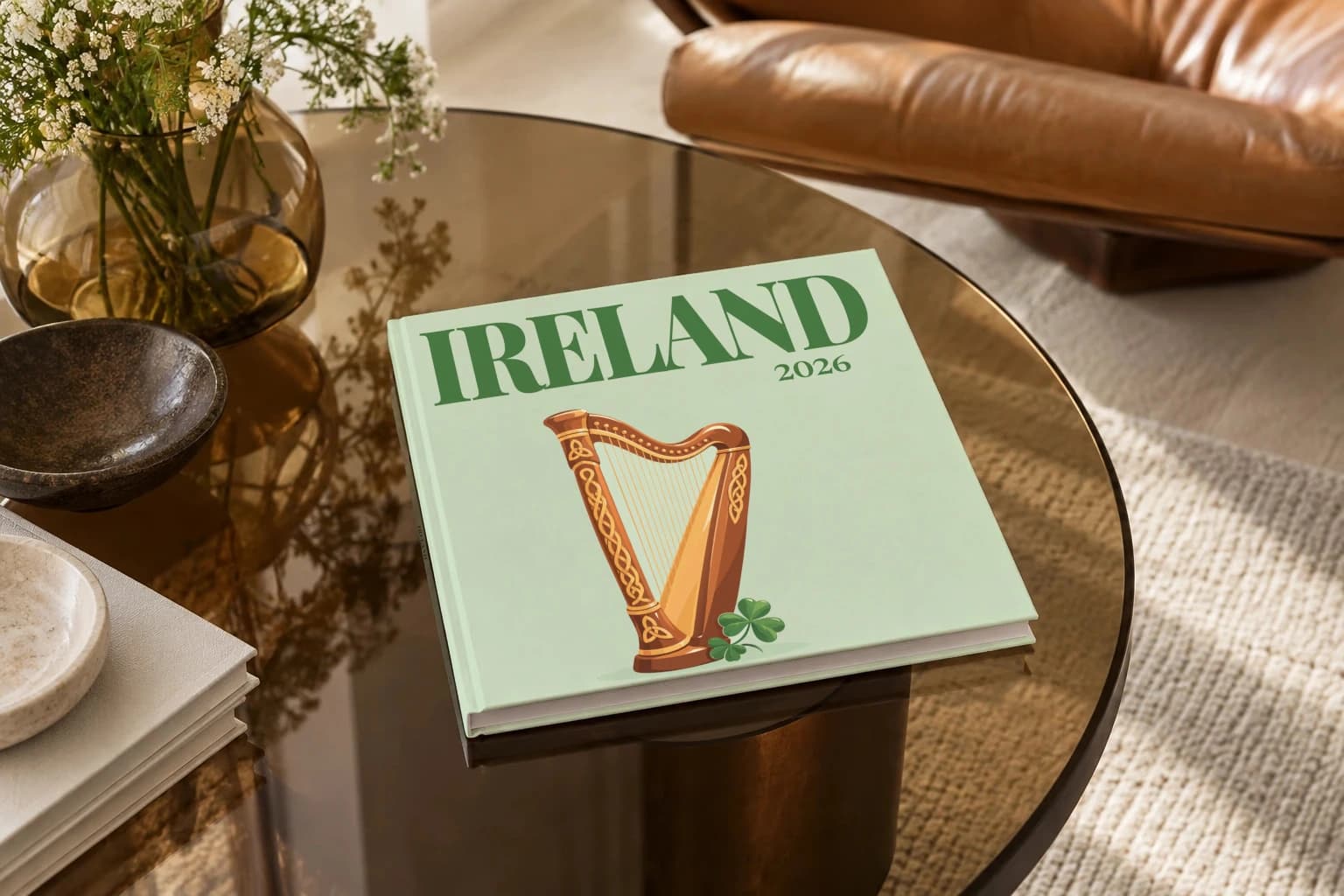 Ireland square hardcover photo book with the illustrated cover of the Celtic harp, on a smoked glass coffee table beside a leather armchair in warm afternoon light