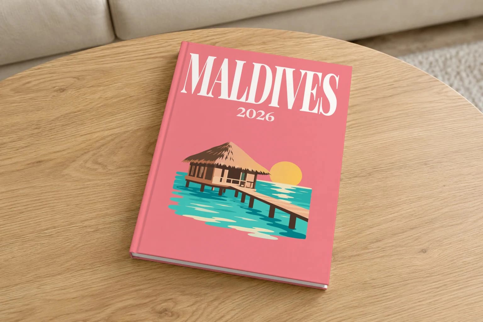 Maldives hardcover photo book with the illustrated cover of the water villa, on a round oak coffee table in a bright living room