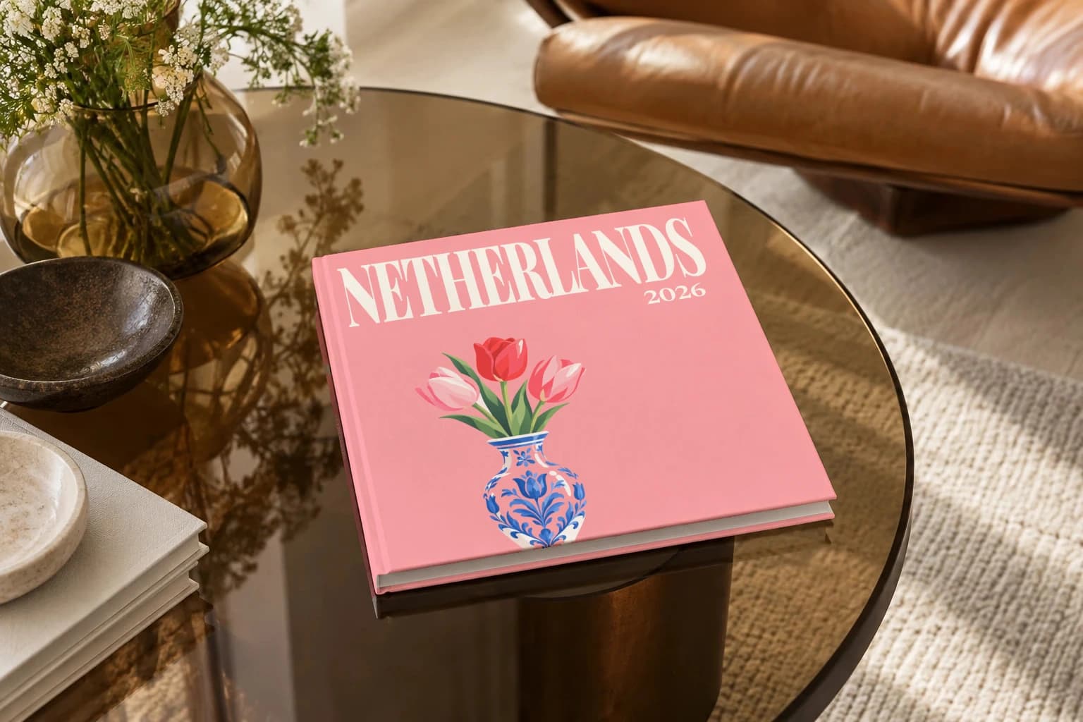 Netherlands square hardcover photo book with the illustrated cover of the tulips, on a smoked glass coffee table beside a leather armchair in warm afternoon light