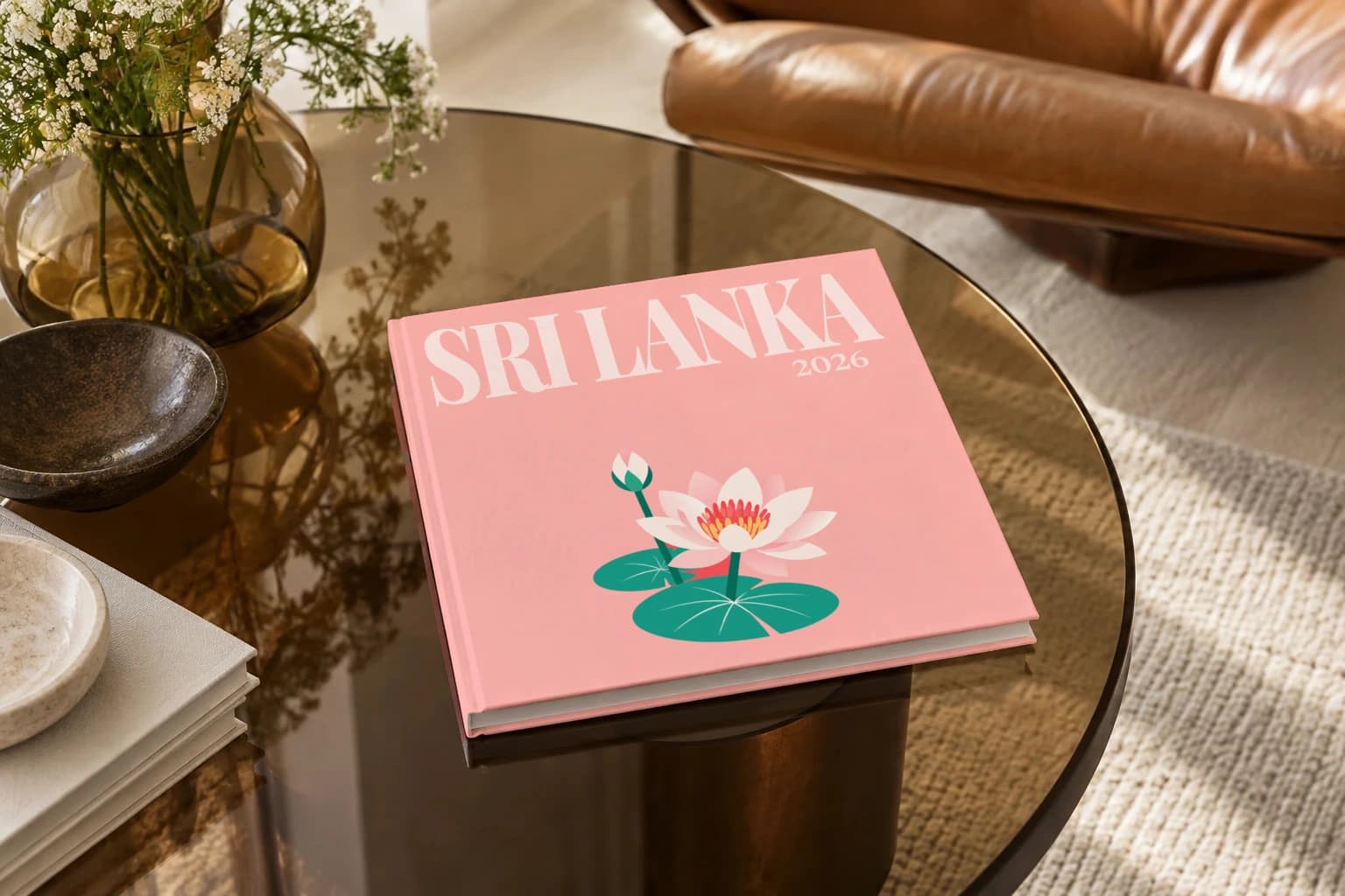 Sri Lanka square hardcover photo book with the illustrated cover of the lotus, on a smoked glass coffee table beside a leather armchair in warm afternoon light