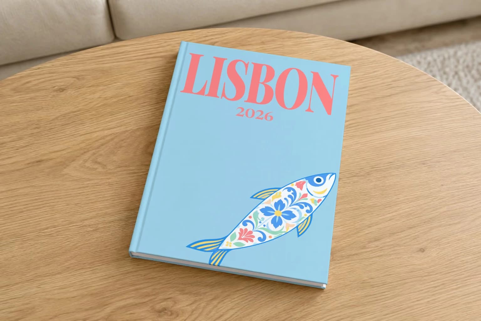 Lisbon hardcover photo book with an illustrated cover of a sardine painted like azulejo tiles, on a round oak coffee table in a bright living room