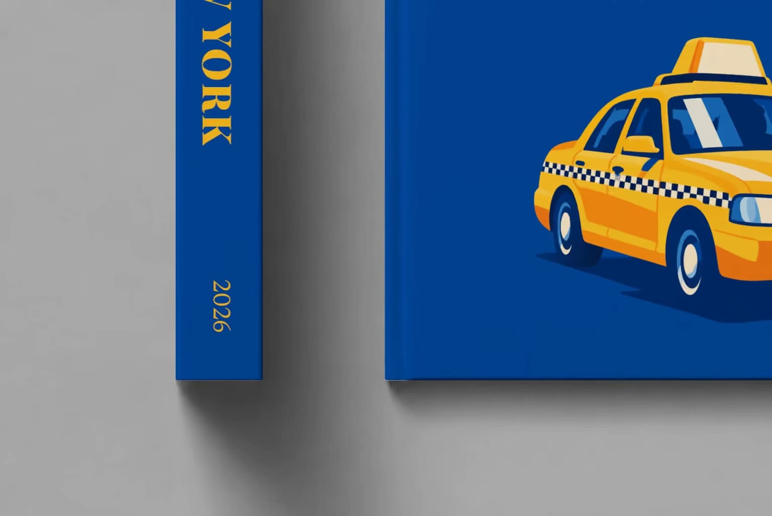 New York hardcover photo book with an illustrated cover of a yellow taxi on royal blue, shown close up beside its spine on a pale grey studio surface