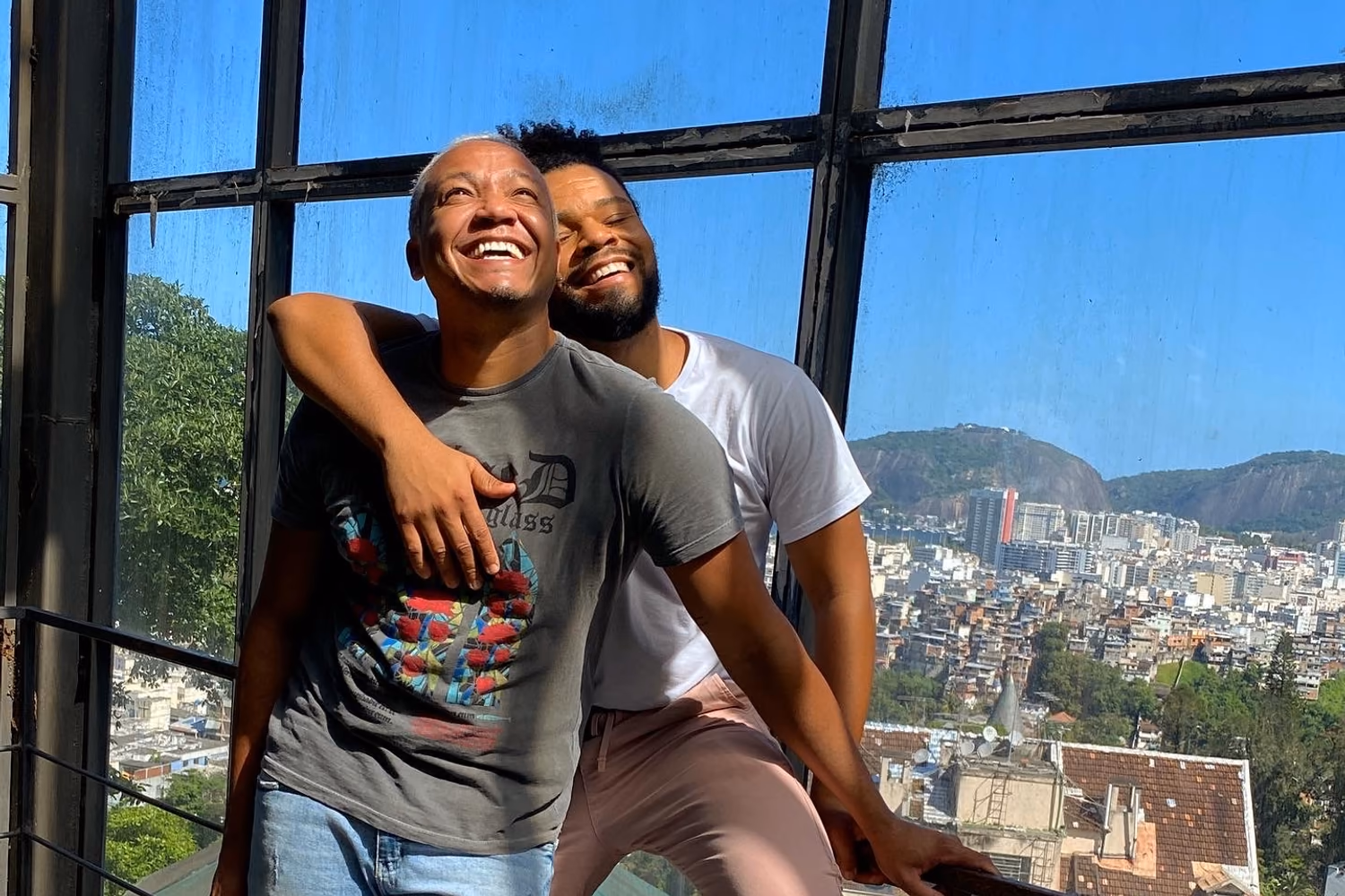 Two people embracing beside a window overlooking a city