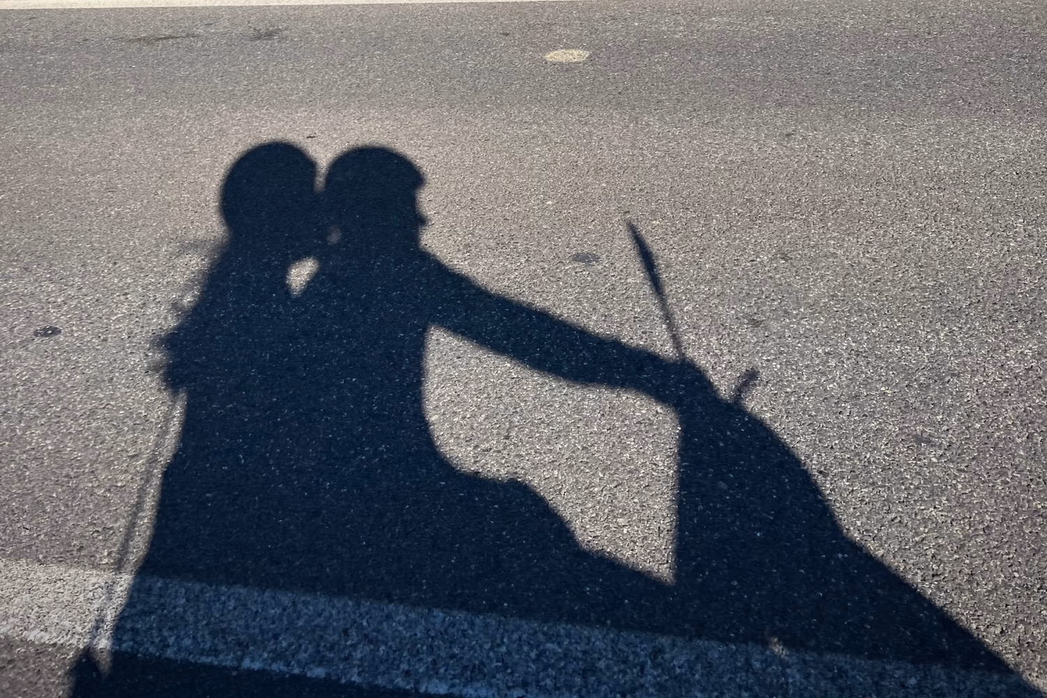 Shadows of two scooter riders on a sunlit road