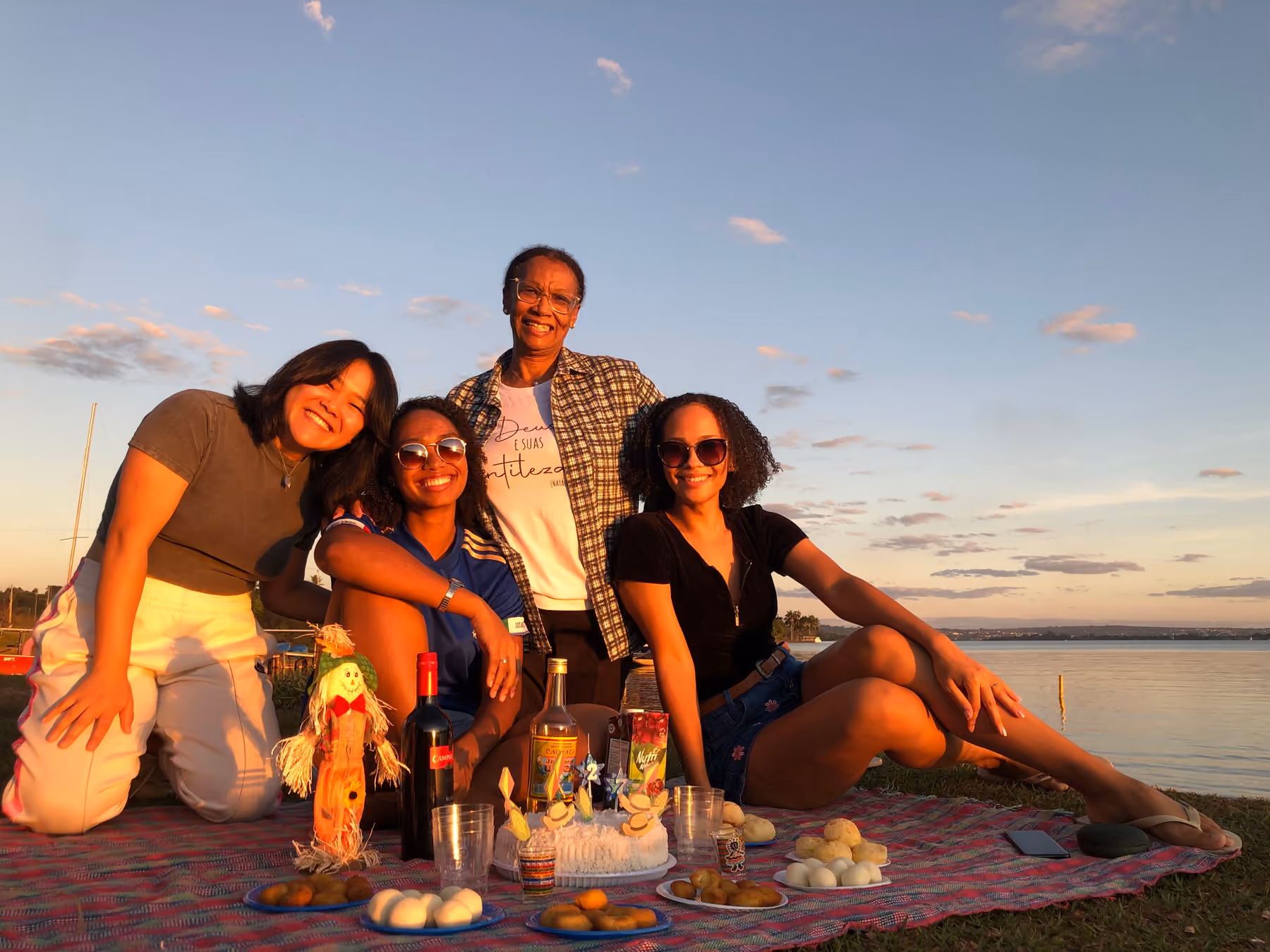 Three generations of one family sharing a birthday picnic by a lake at sunset, the kind of gathering where travel stories get told