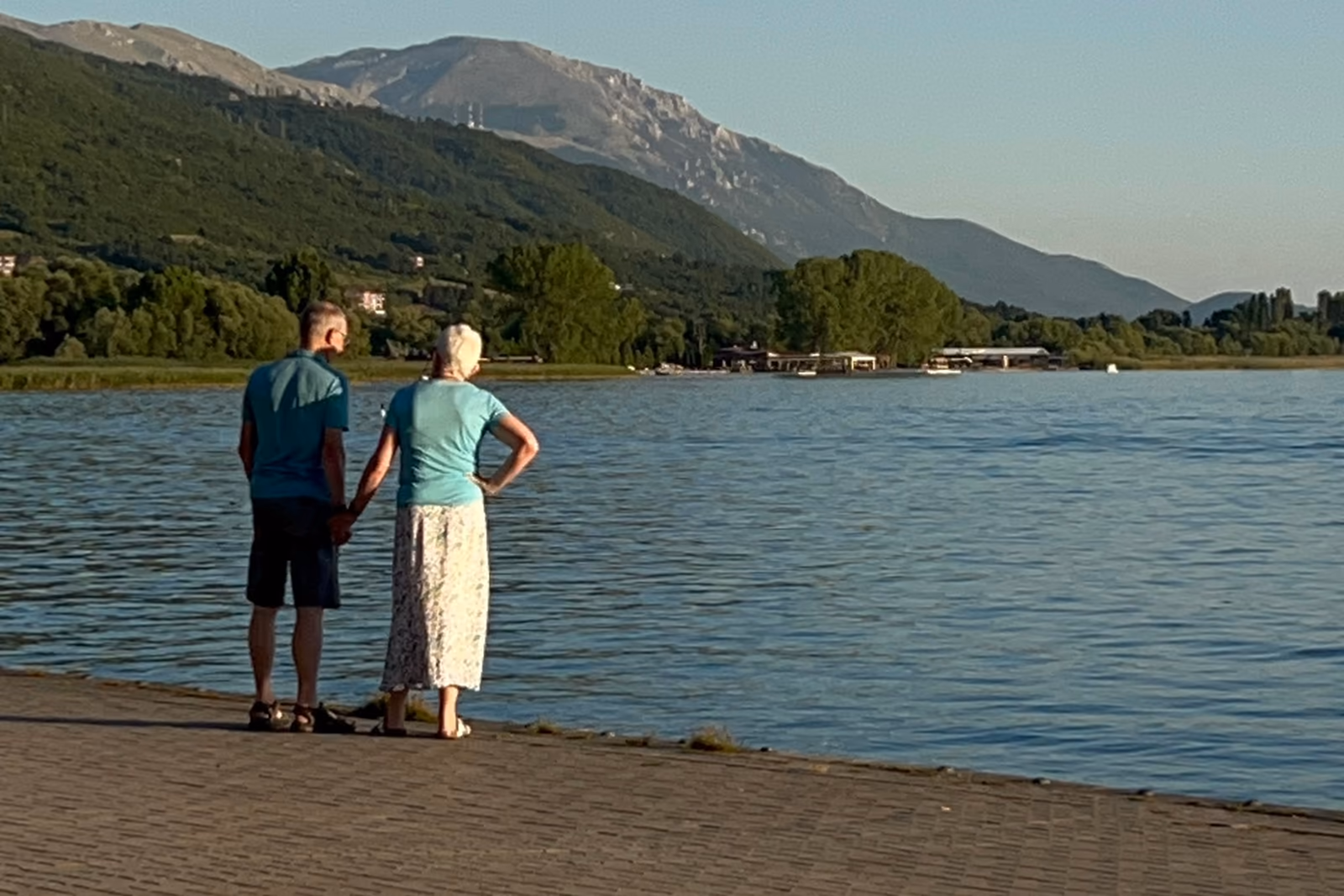 Couple holding hands beside a lake with mountains beyond