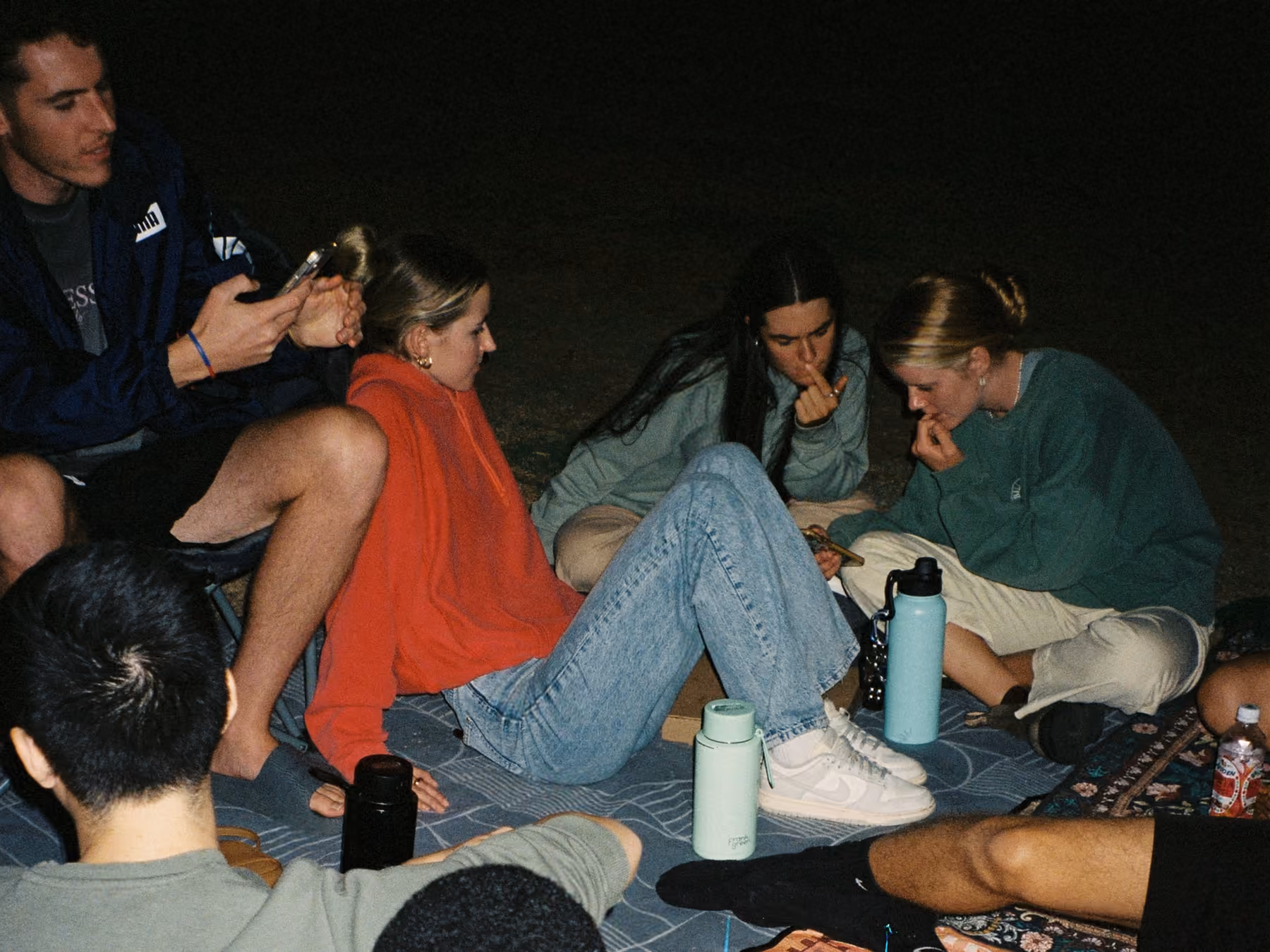Erasmus friends sitting on blankets outdoors at night, a film photo of the kind of evening a shared study abroad journal keeps