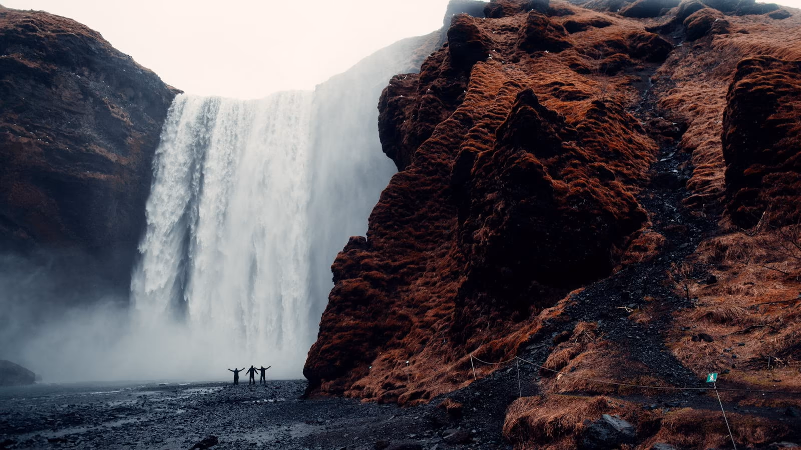 Travellers standing beside a large waterfall in Iceland