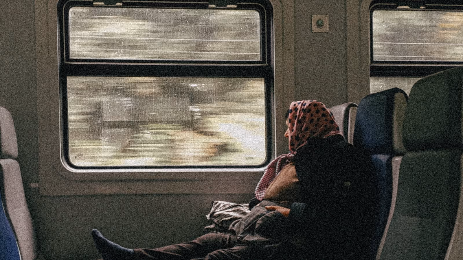 A rail passenger looking through a train window