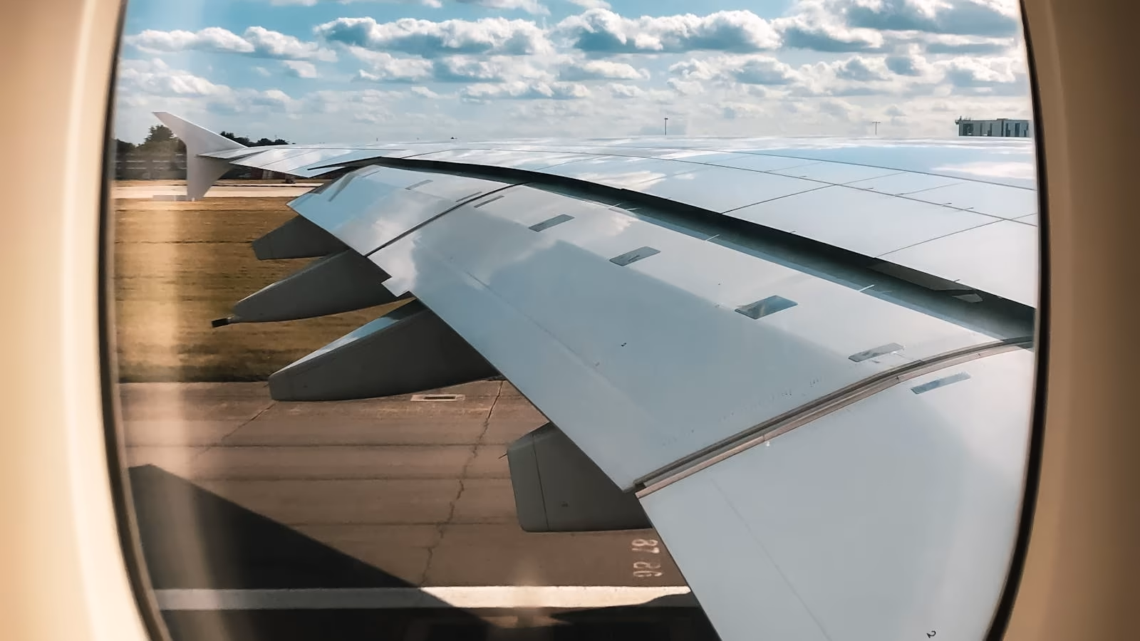 An aeroplane wing seen from a passenger window on the runway