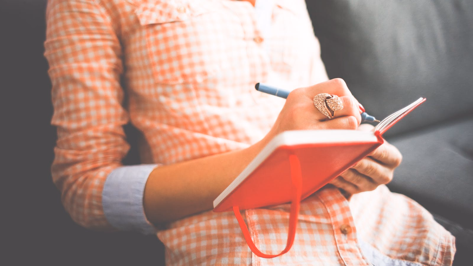 A woman writing in a red notebook while travelling