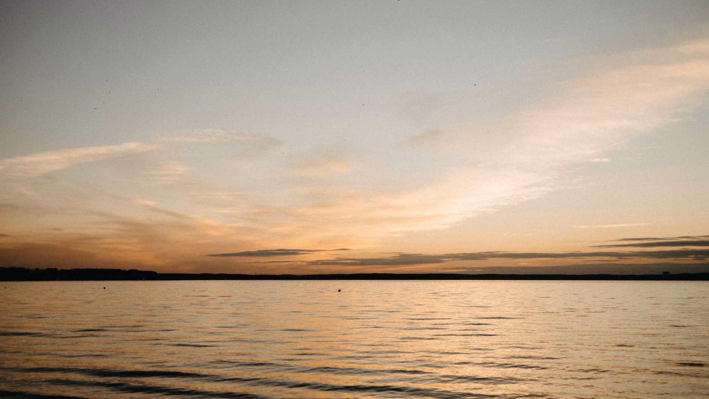 A calm sea beneath a soft sunset sky