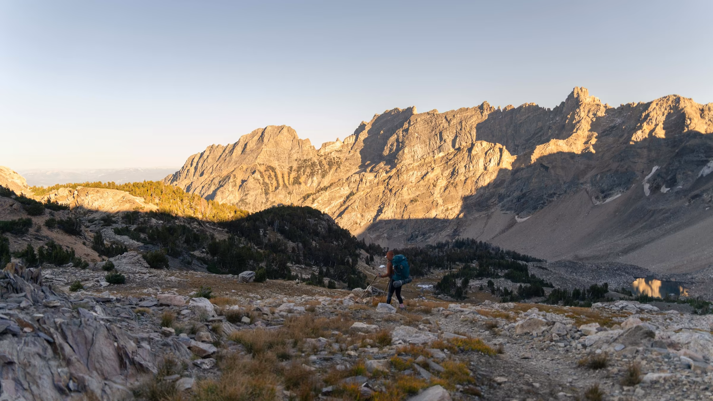 A solo hiker crossing rugged mountain terrain