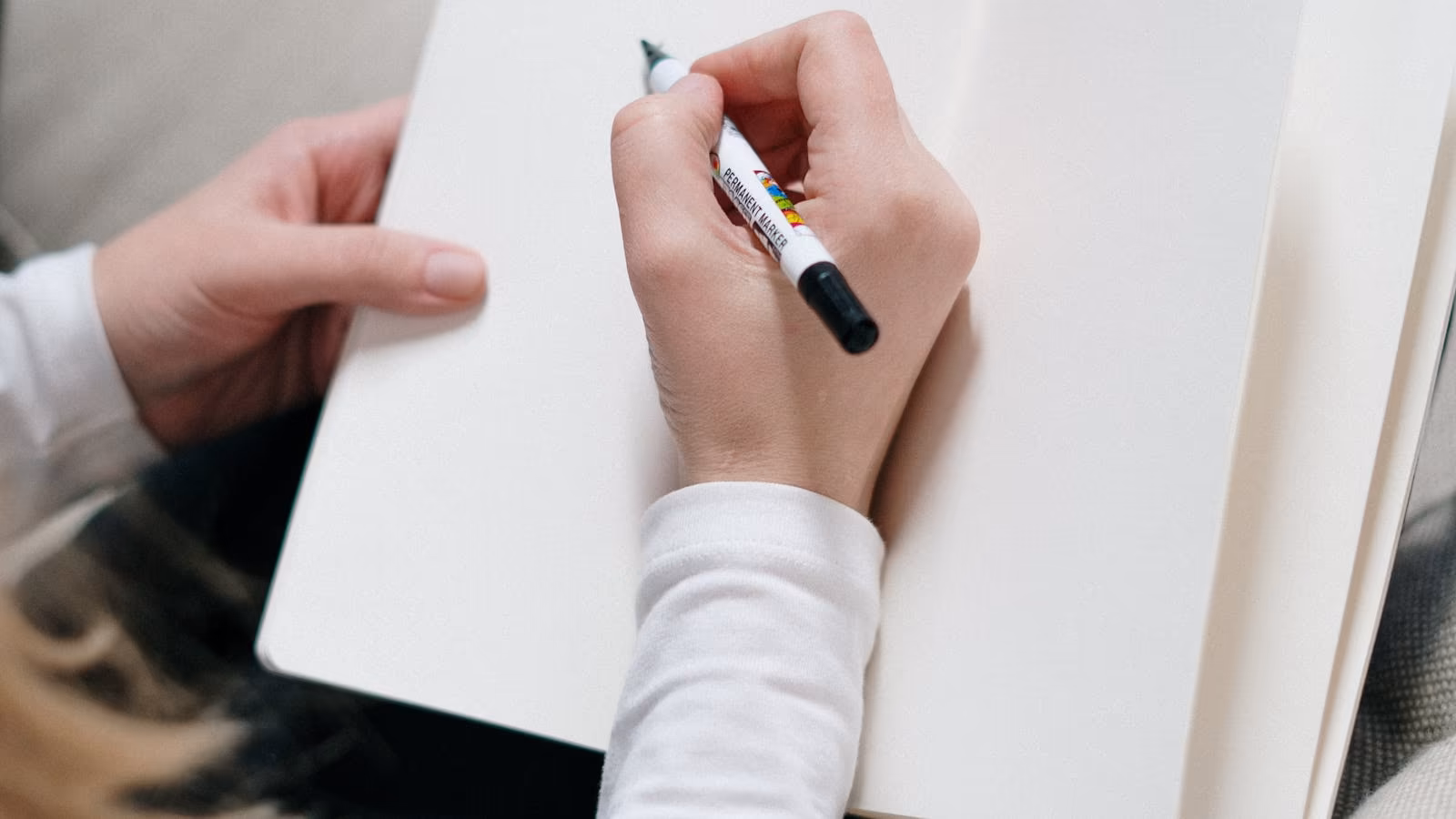 A hand writing prompts in an open notebook
