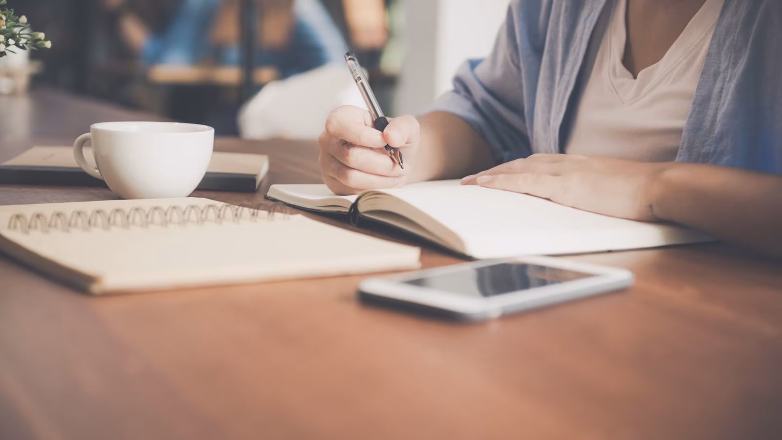 A woman writing in a notebook at a table