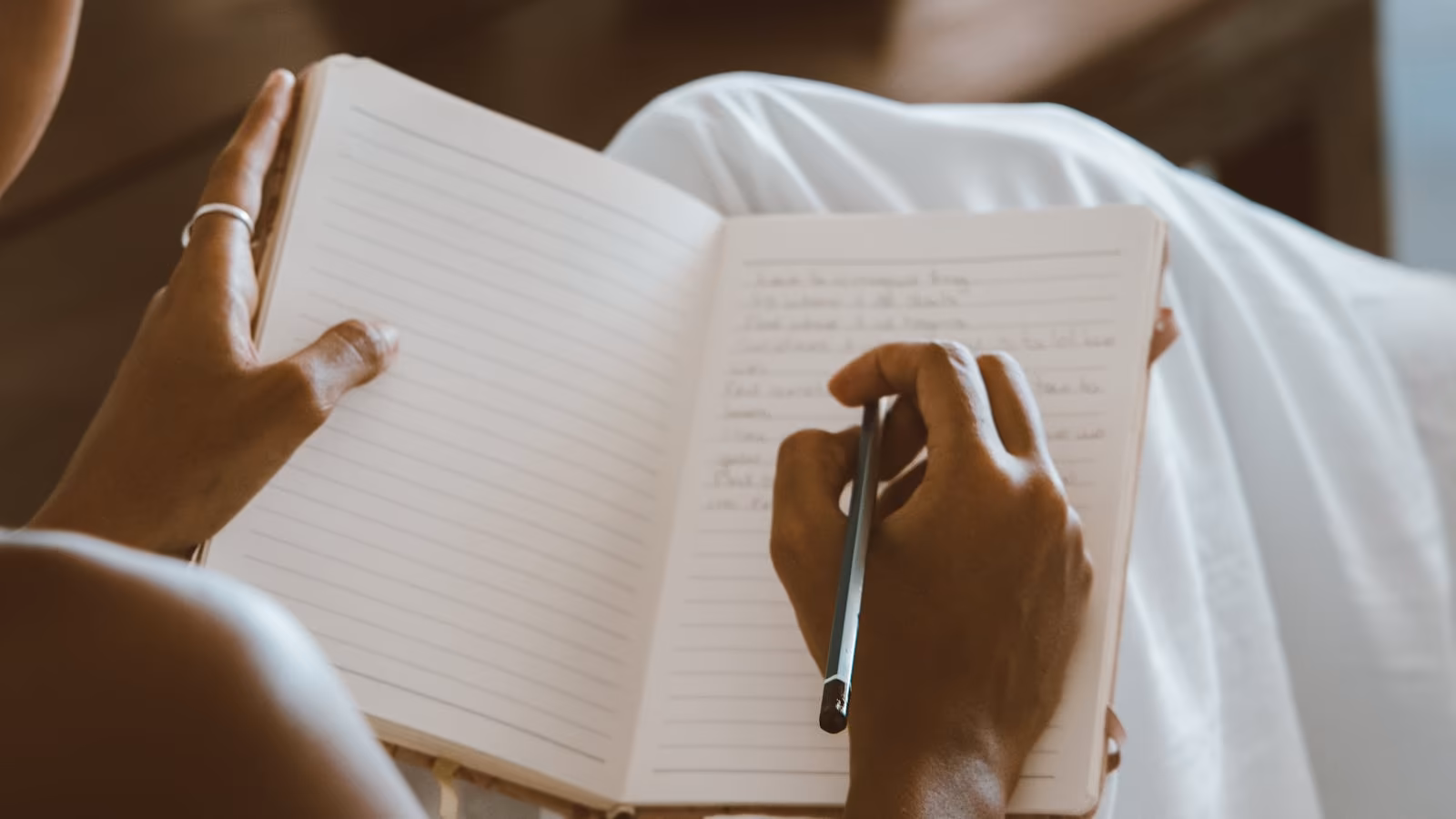Hands writing in an open travel notebook