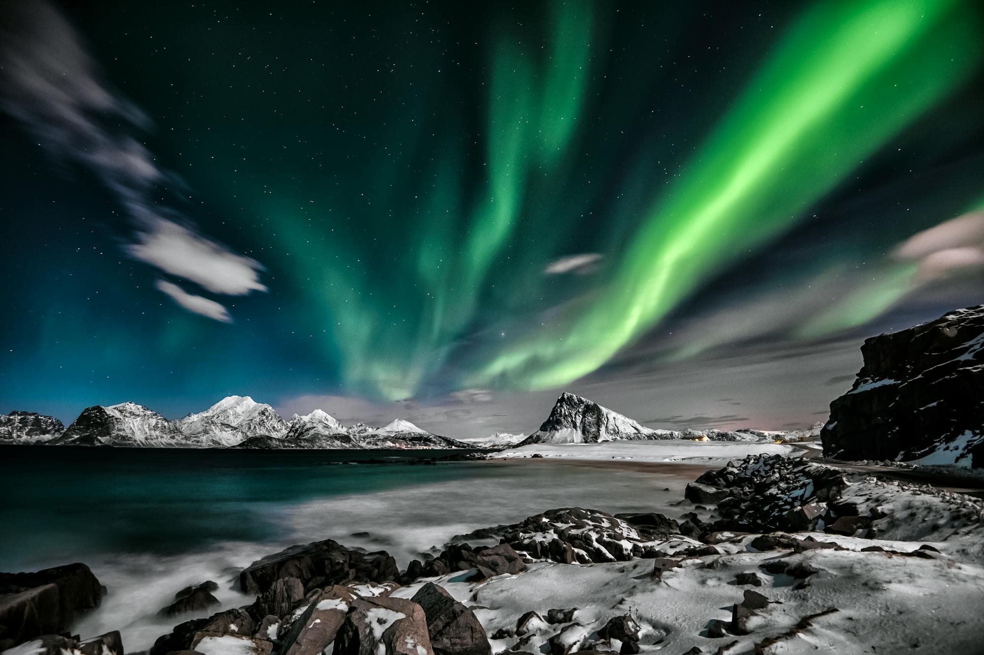 Green Aurora Borealis swirling above a snow-covered Icelandic landscape