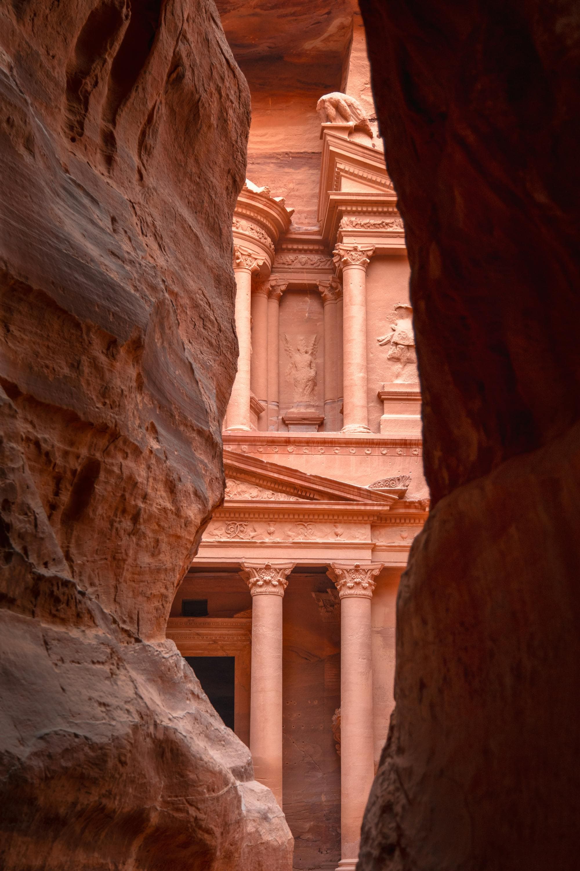 The Treasury façade carved into red sandstone at Petra, Jordan, glowing in afternoon light