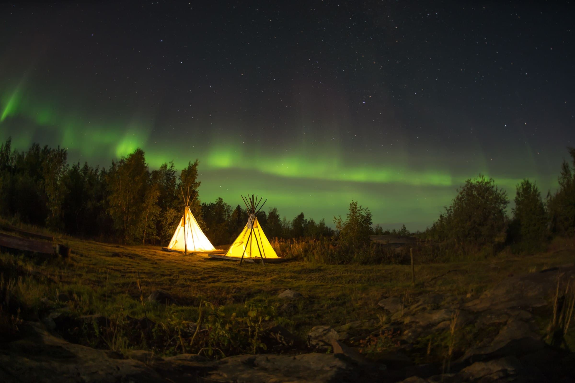 Northern lights above illuminated lodges near Yellowknife