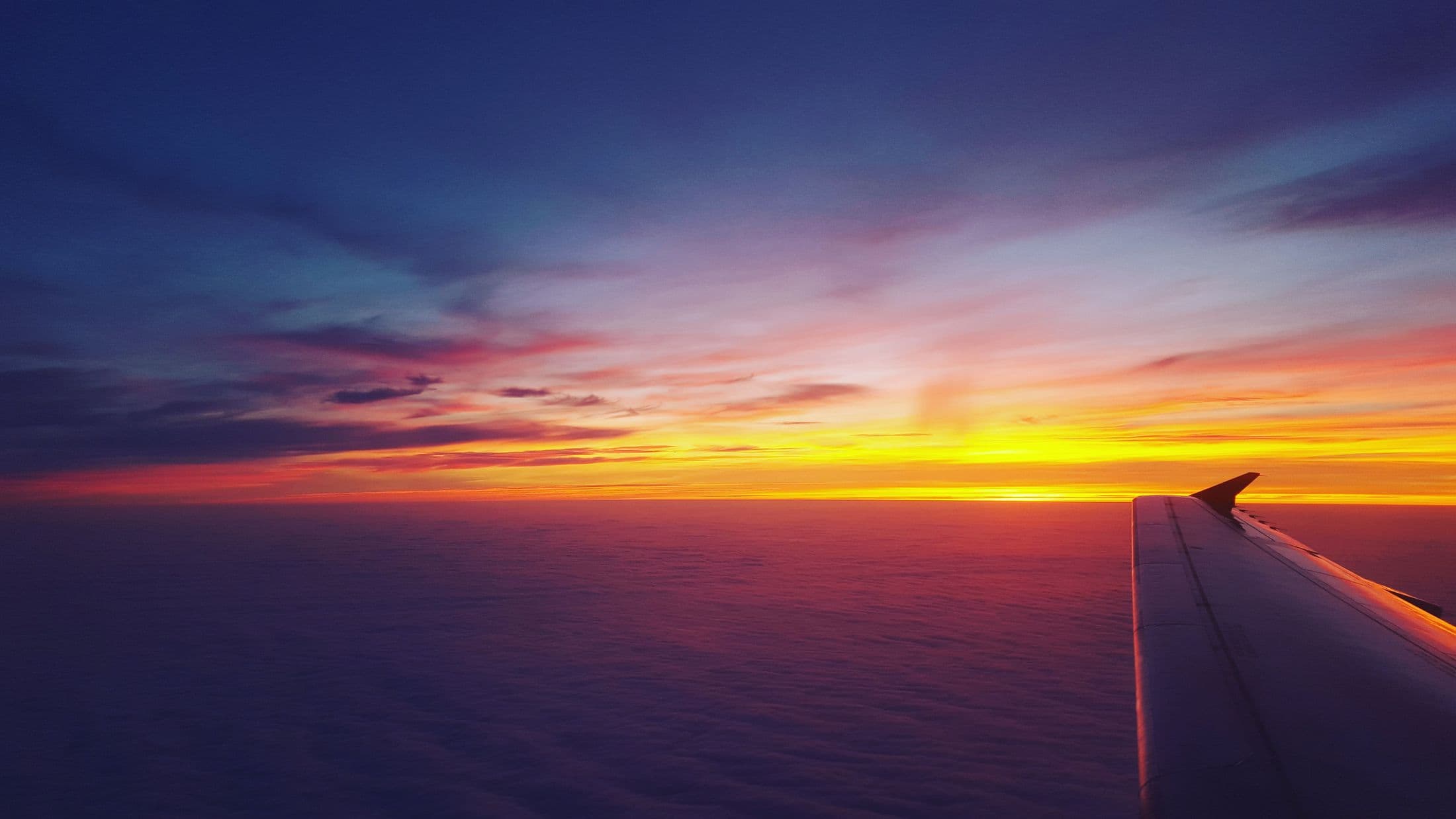 Airplane wing above the ocean during a vivid sunset