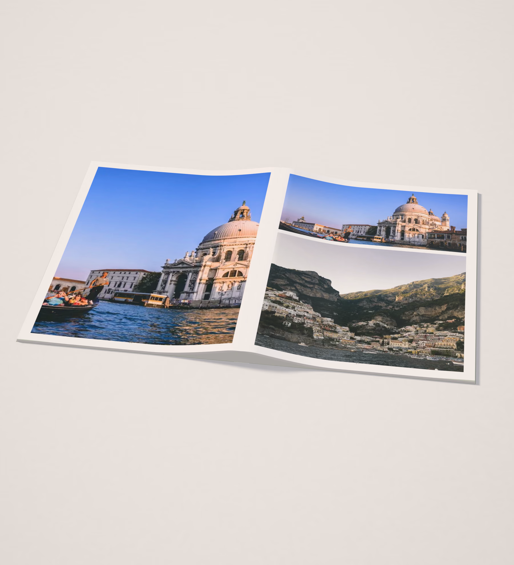 Softcover travel photo book lying open on a pale studio table, with Venice and Amalfi Coast photos across its pages