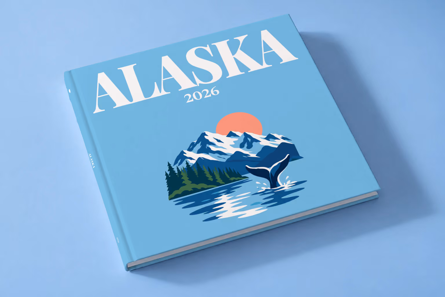 Alaska square hardcover photo book with the illustrated cover of a whale tail before snowy mountains and pine forest on sky blue, lying on a pale blue studio backdrop