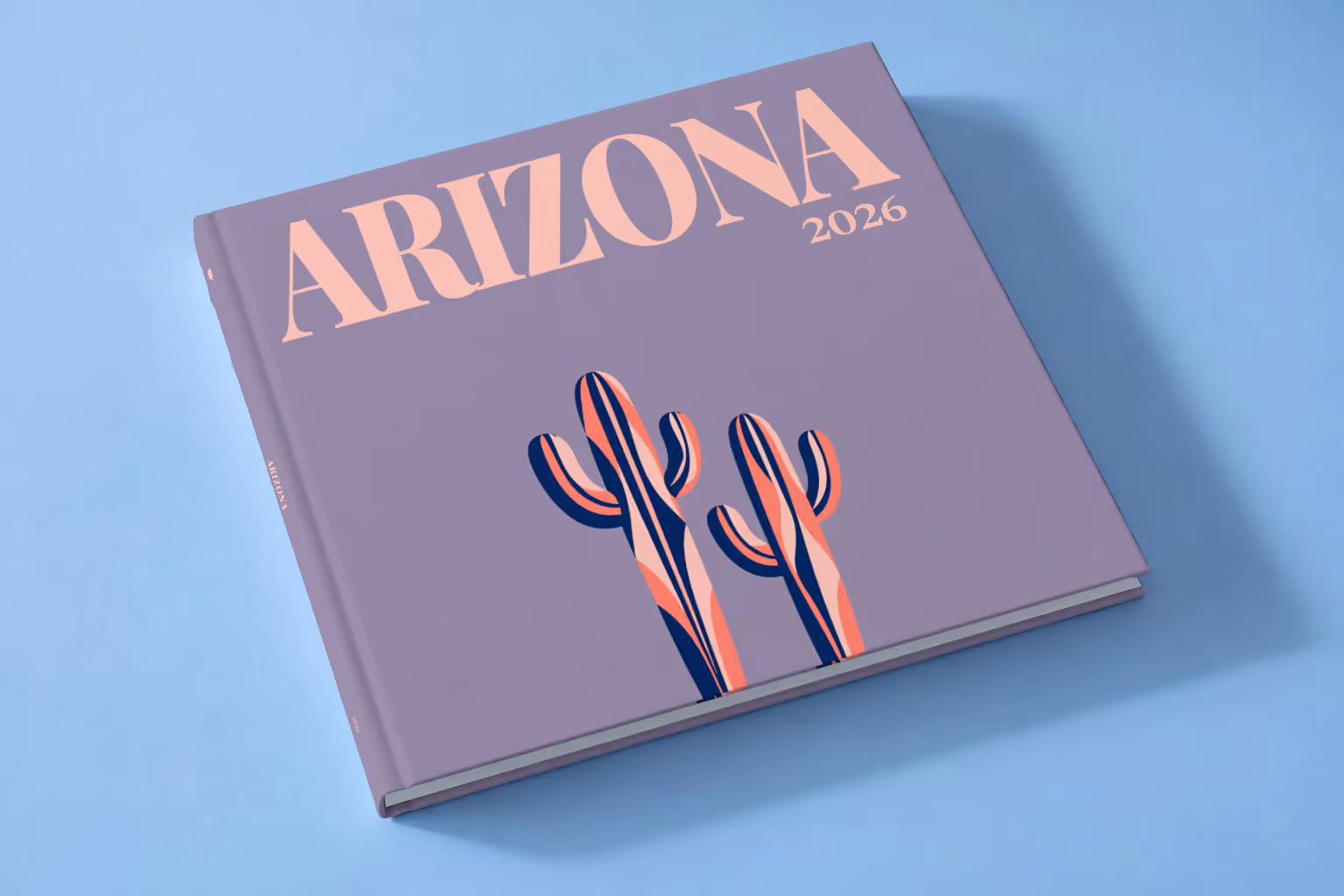 Arizona square hardcover photo book with the illustrated cover of two stylised saguaro cacti on dusty purple, lying on a pale blue studio backdrop