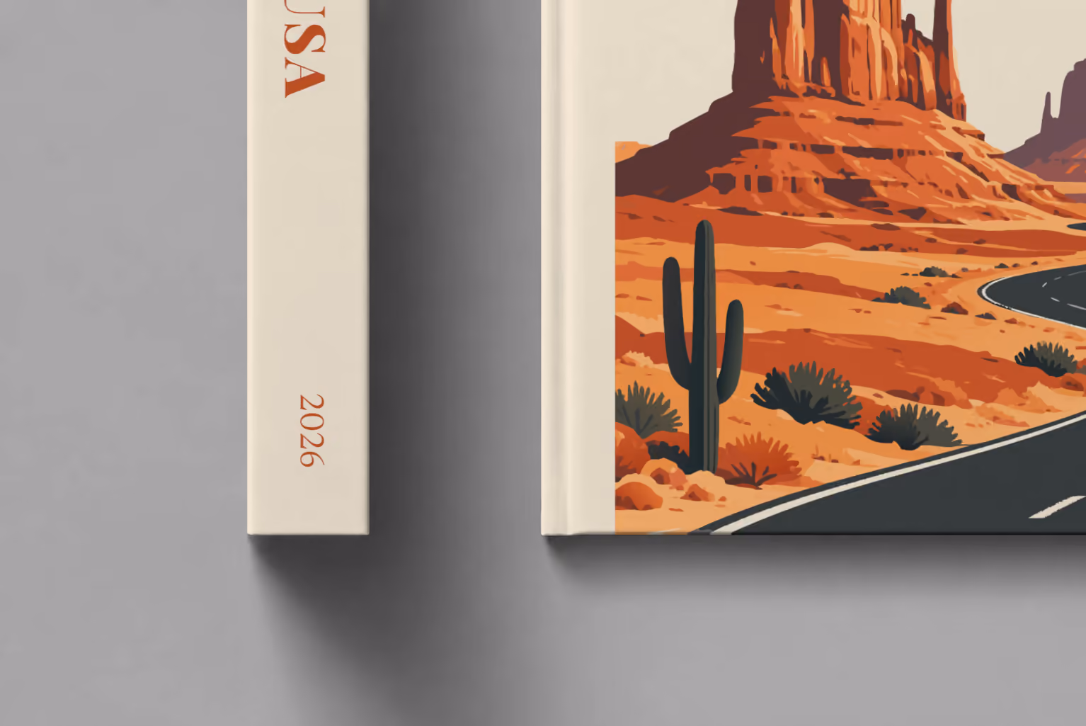 Arizona hardcover photo book with the USA illustrated cover of the road through the red buttes of Monument Valley on sand, shown close up beside its spine on a pale grey studio surface