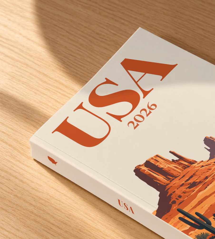 Arizona softcover photo book with the USA illustrated cover of the road through the red buttes of Monument Valley on sand, lying on an oak desk in dappled afternoon sunlight