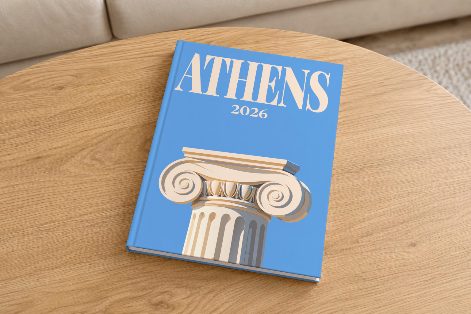 Athens hardcover photo book with the illustrated cover of an Ionic capital on blue, on a round oak coffee table in a bright living room