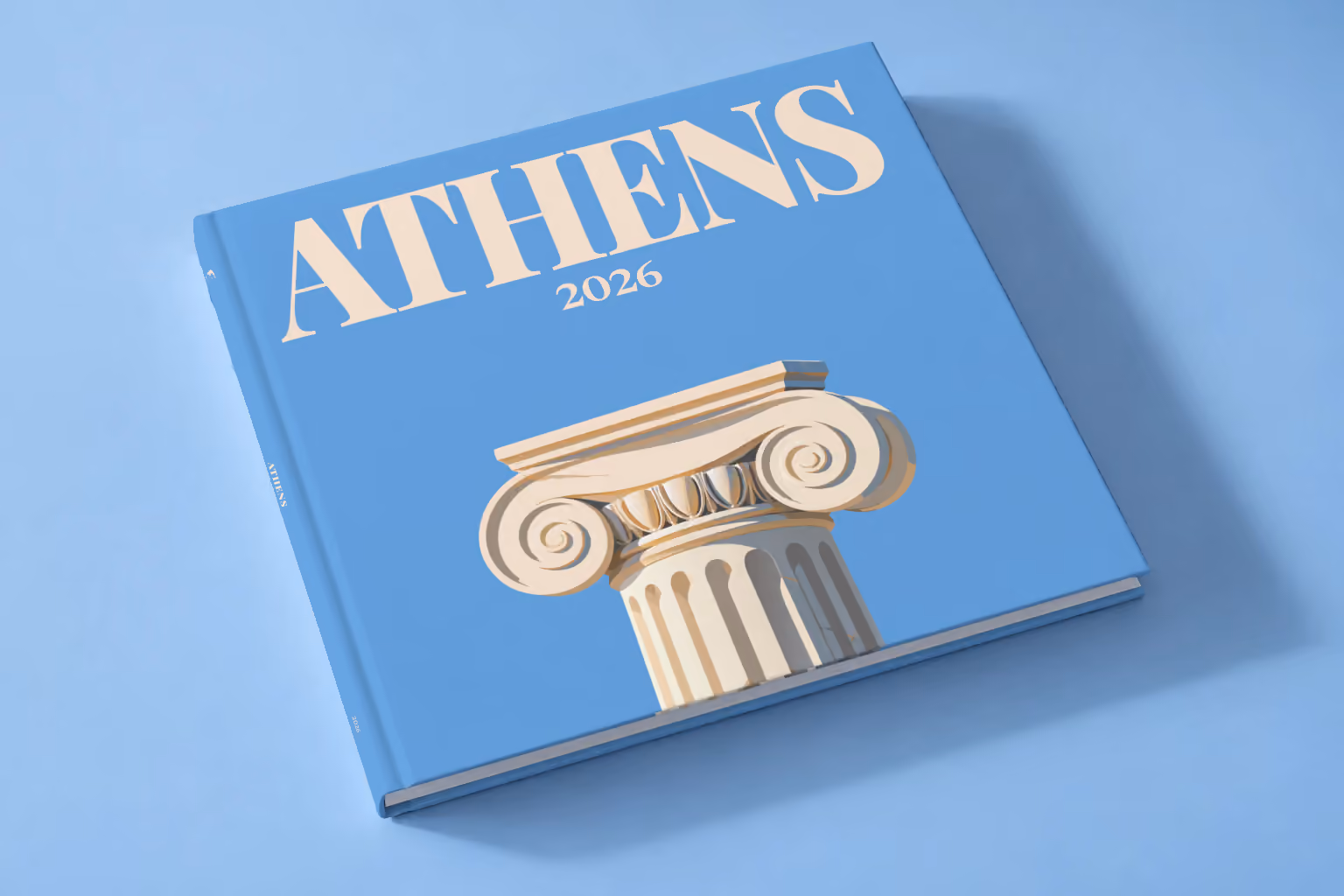 Athens square hardcover photo book with the illustrated cover of an Ionic capital on blue, lying on a pale blue studio backdrop
