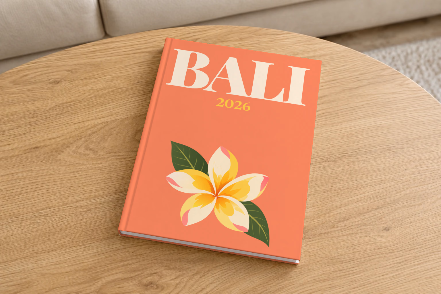 Bali hardcover photo book with the illustrated cover of a yellow frangipani flower on coral, on a round oak coffee table in a bright living room