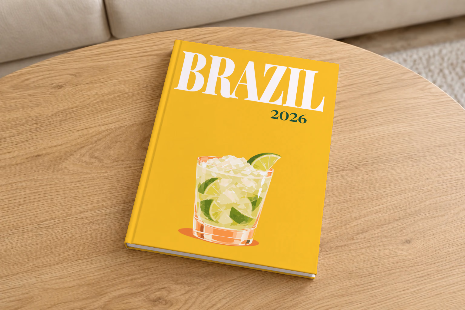 Brazil hardcover photo book with the illustrated cover of a caipirinha with crushed ice and lime on golden yellow, on a round oak coffee table in a bright living room