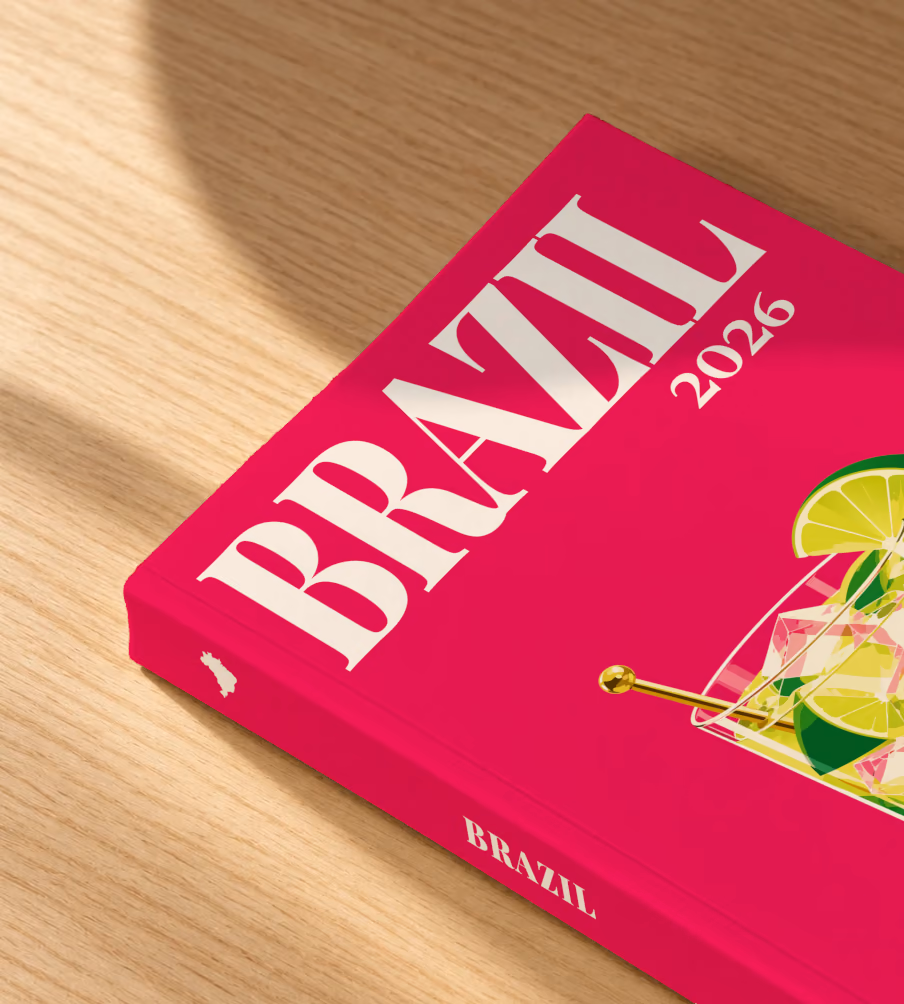 Brazil softcover photo book with the illustrated cover of a caipirinha with lime wedges on magenta, lying on an oak desk in dappled afternoon sunlight