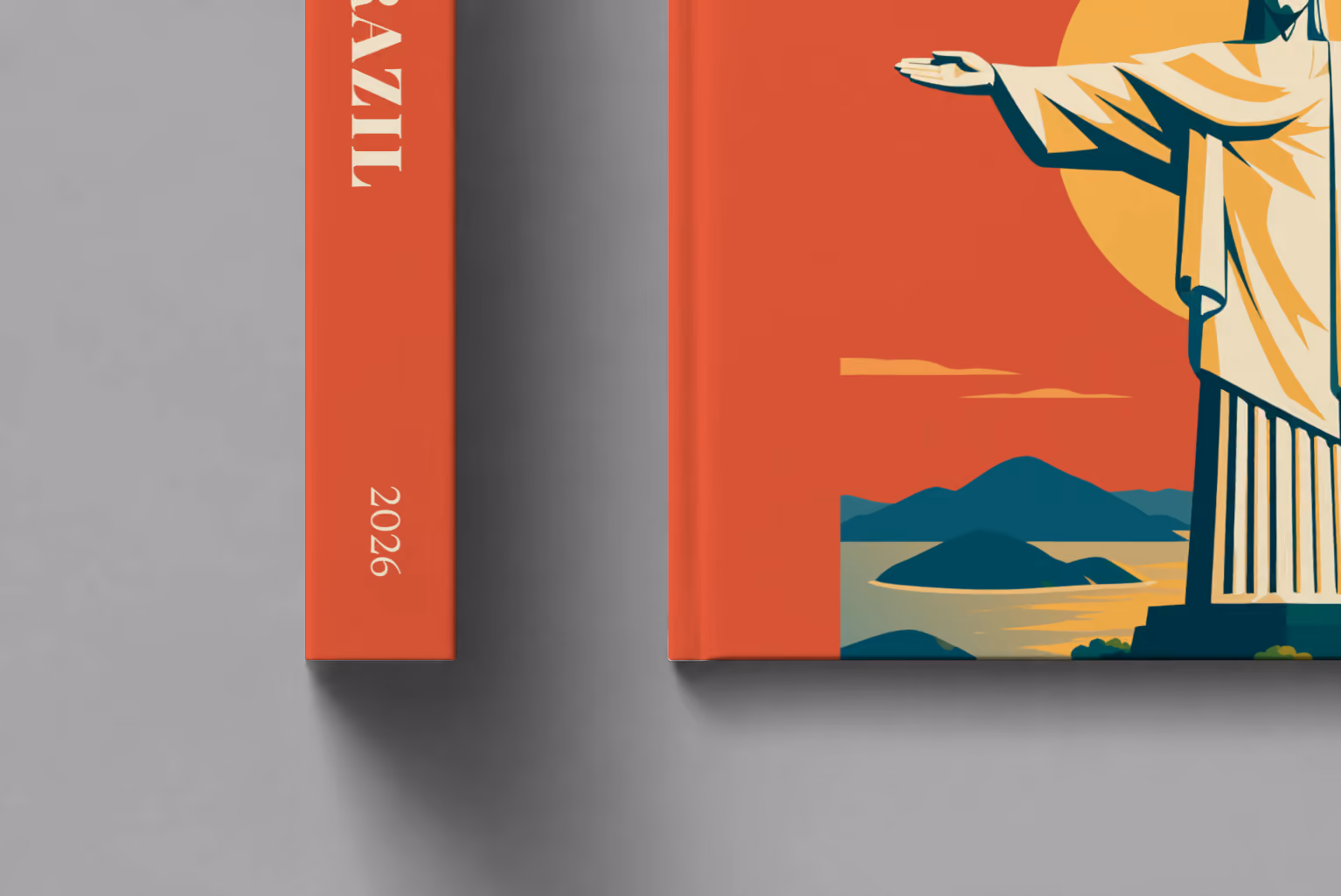 Brazil hardcover photo book with the illustrated cover of Christ the Redeemer above Rio de Janeiro's bay at sunset on red-orange, shown close up beside its spine on a pale grey studio surface