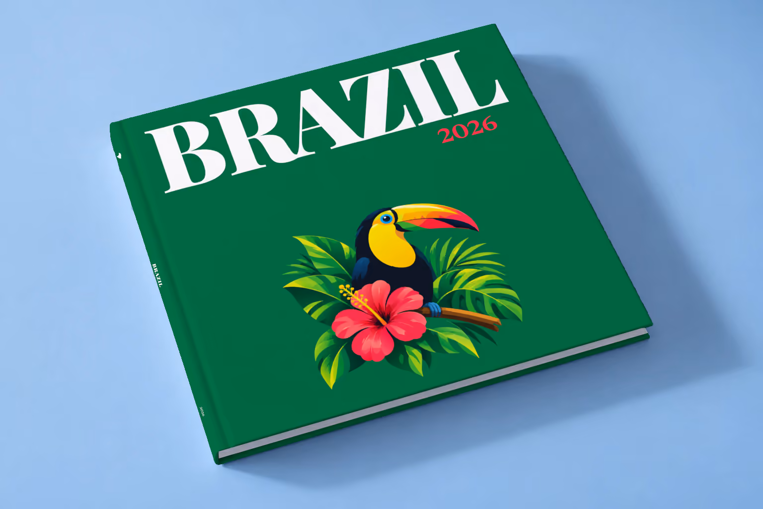 Brazil square hardcover photo book with the illustrated cover of a toucan among tropical leaves and a pink hibiscus on emerald green, lying on a pale blue studio backdrop