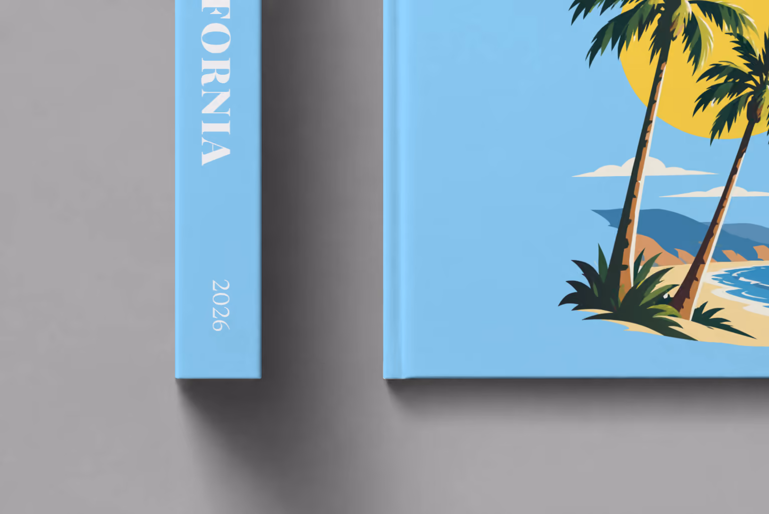 California hardcover photo book with the illustrated cover of palm trees and a beach under a yellow sun on sky blue, shown close up beside its spine on a pale grey studio surface