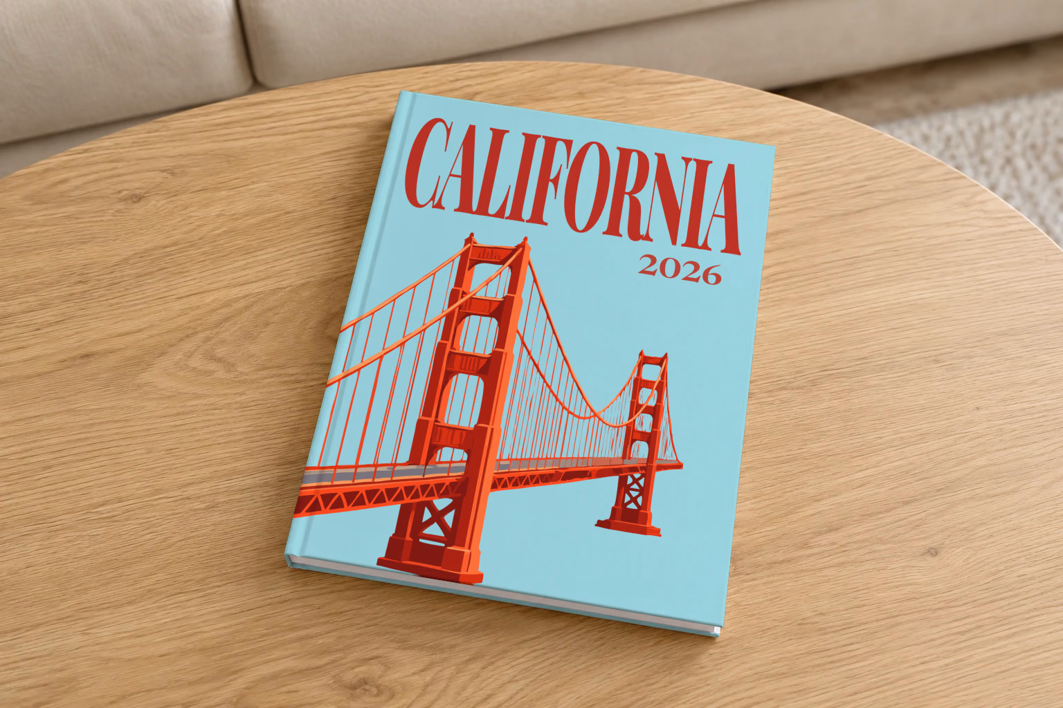 California hardcover photo book with the illustrated cover of the Golden Gate Bridge on pale aqua, on a round oak coffee table in a bright living room