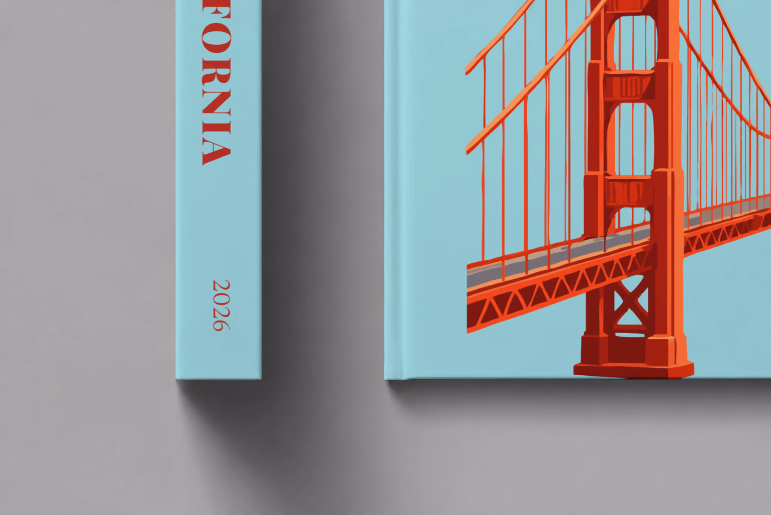 California hardcover photo book with the illustrated cover of the Golden Gate Bridge on pale aqua, shown close up beside its spine on a pale grey studio surface