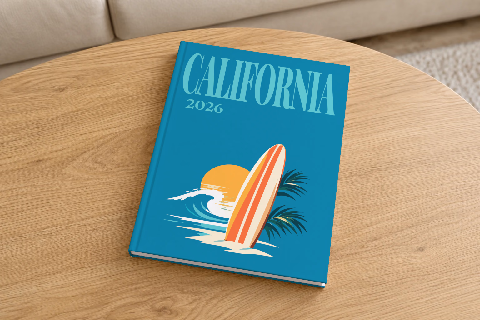 California hardcover photo book with the illustrated cover of a surfboard, a wave and the sun on teal, on a round oak coffee table in a bright living room