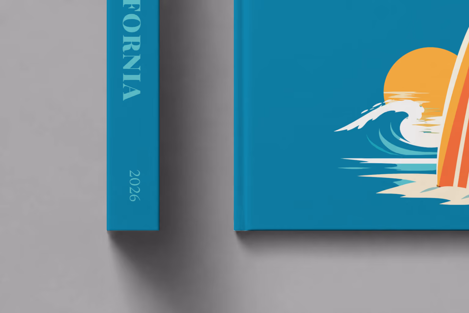 California hardcover photo book with the illustrated cover of a surfboard, a wave and the sun on teal, shown close up beside its spine on a pale grey studio surface