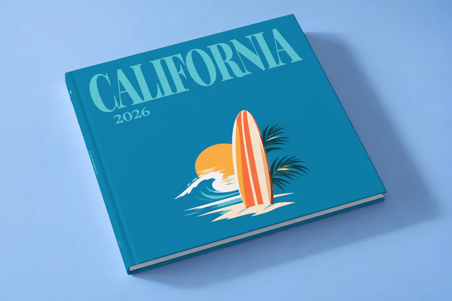 California square hardcover photo book with the illustrated cover of a surfboard, a wave and the sun on teal, lying on a pale blue studio backdrop
