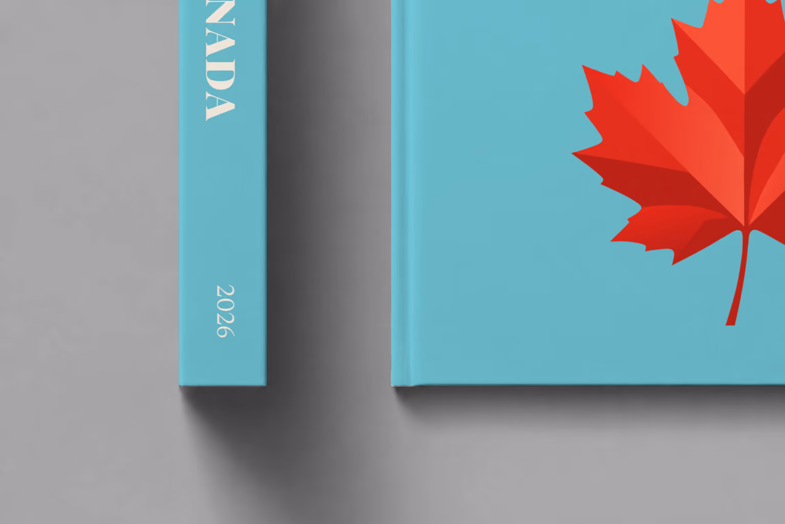 Canada hardcover photo book with the illustrated cover of a red maple leaf on turquoise, shown close up beside its spine on a pale grey studio surface