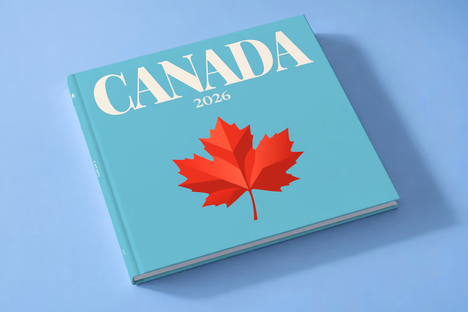 Canada square hardcover photo book with the illustrated cover of a red maple leaf on turquoise, lying on a pale blue studio backdrop