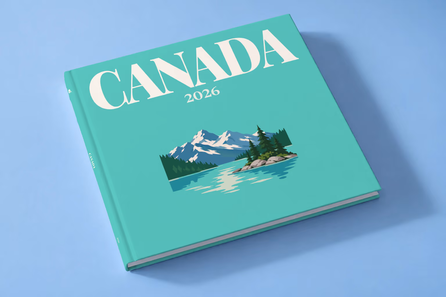 Canada square hardcover photo book with the illustrated cover of a mountain lake with a pine-covered islet on mint green, lying on a pale blue studio backdrop